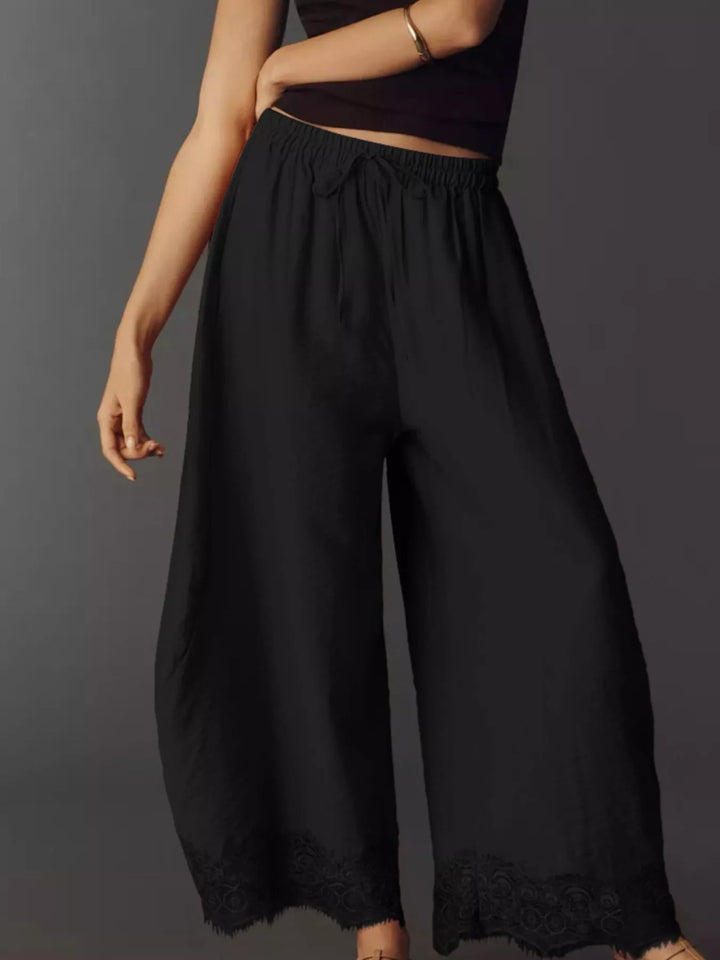 Black drawstring pants in a three quarter view with the tie visible