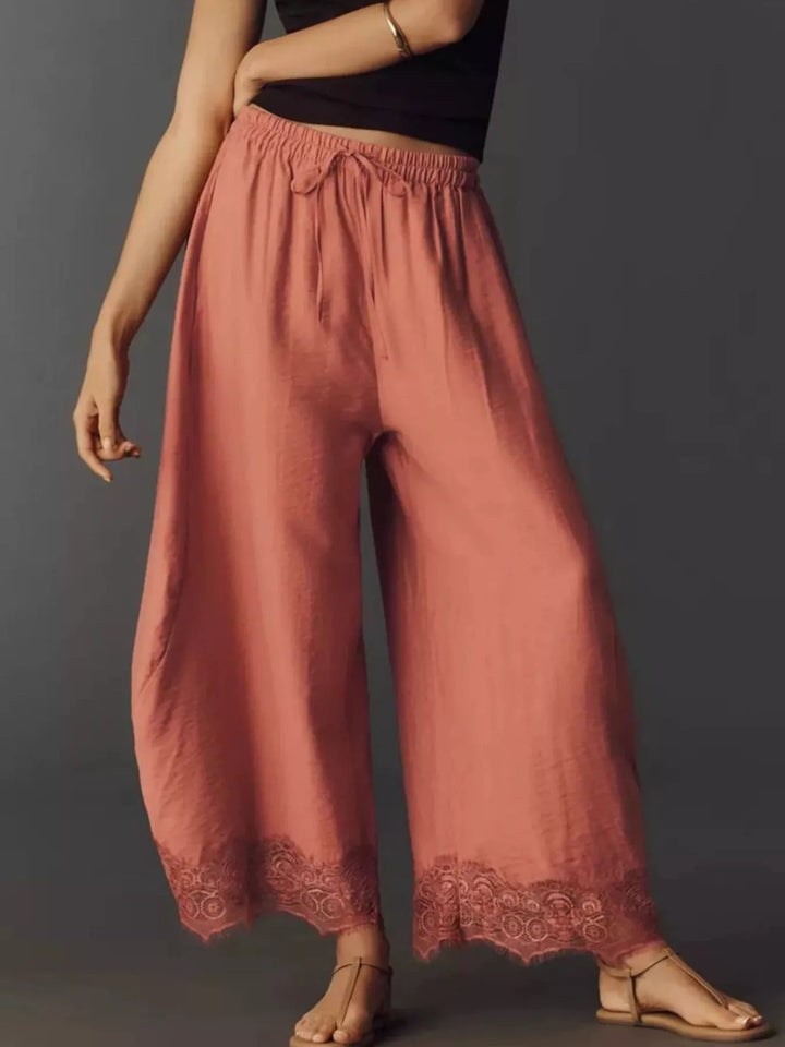 Side view of the burnt coral pants with lace trim hem and sandals