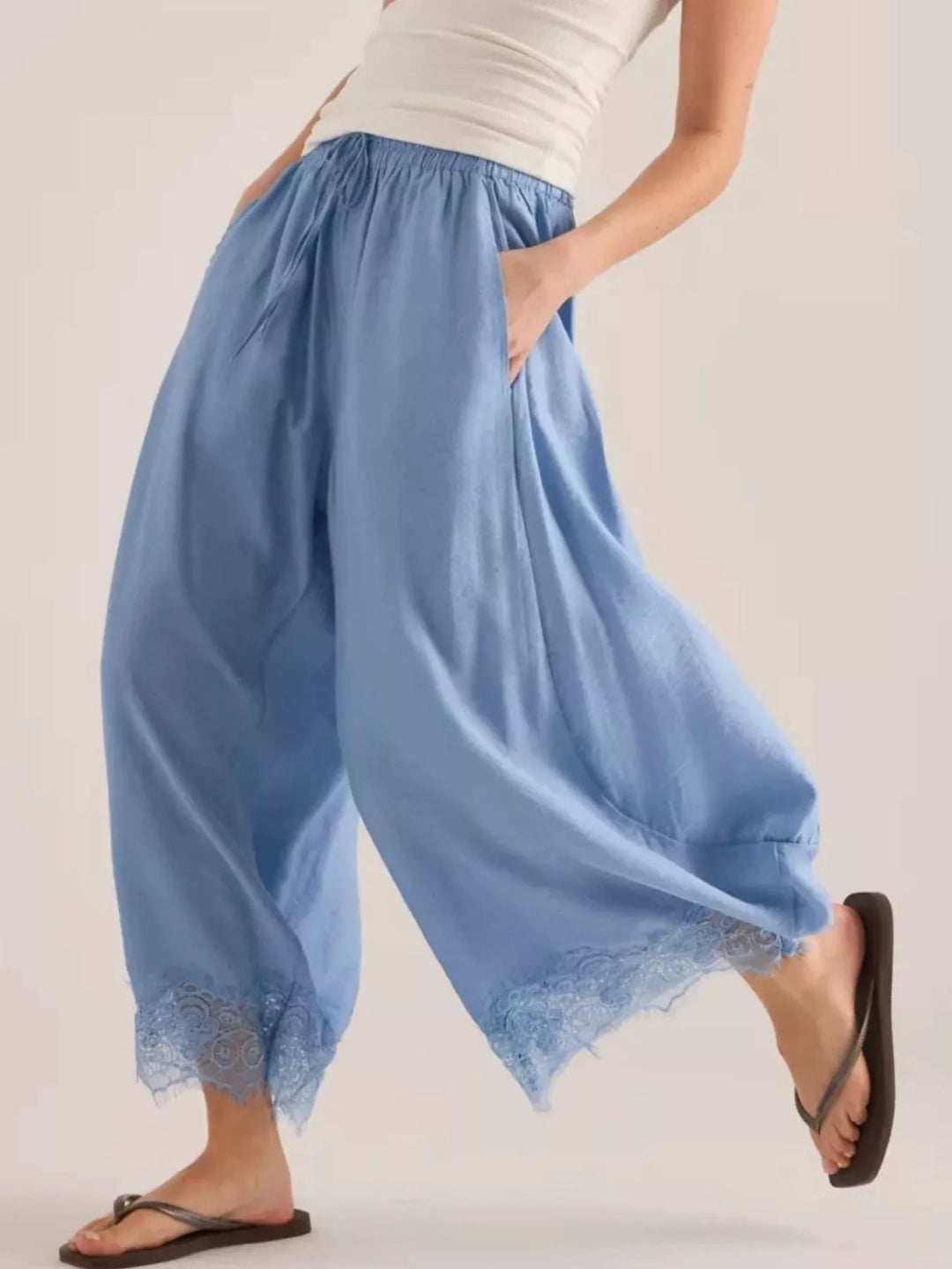Women's wide leg pants in light blue with drawstring waist and lace trim hem, walking