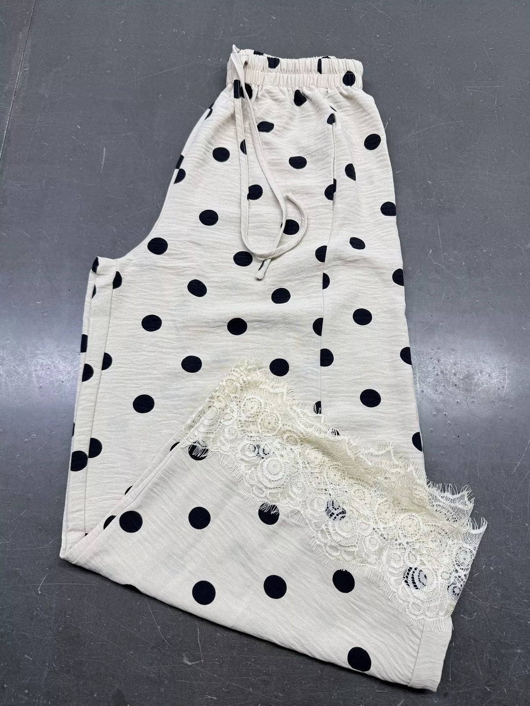 Polka dot wide leg pants laid flat showing the lace trimmed hem