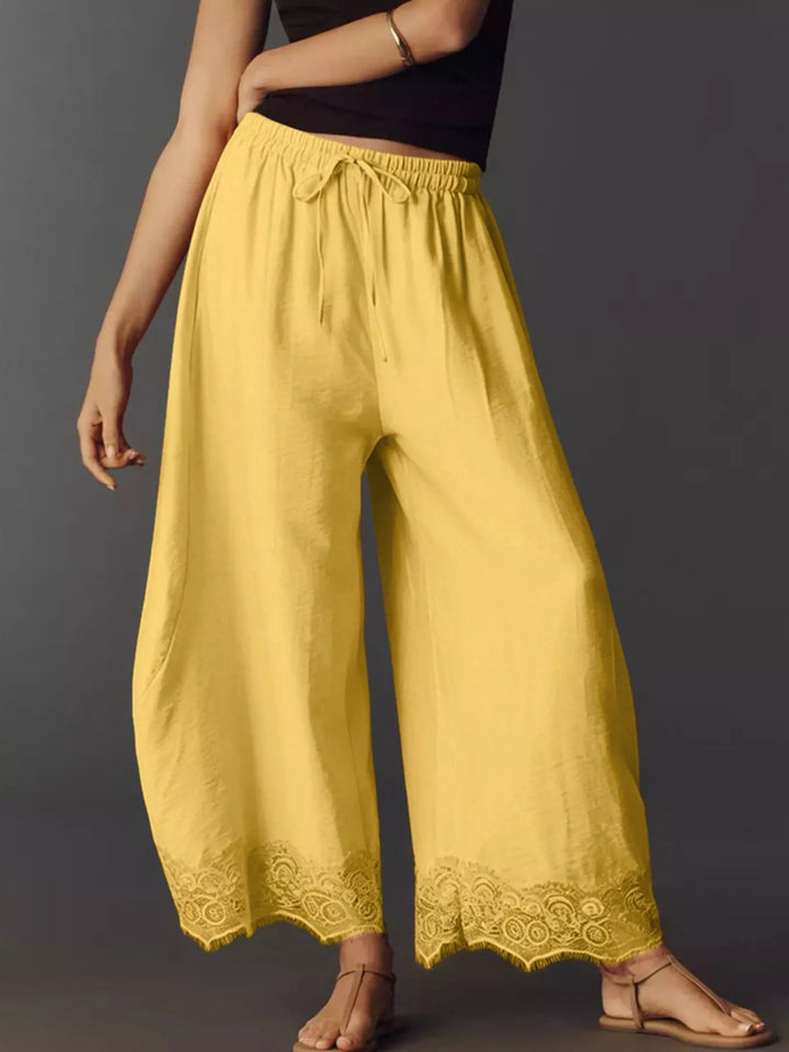 Yellow drawstring pants from the side with lace hem and sandals