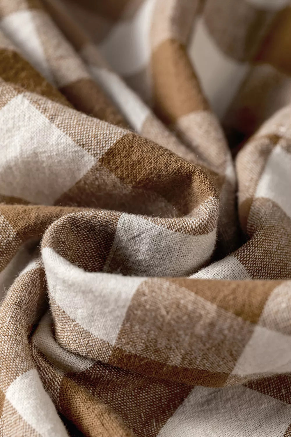 Soft folds of the brown and white gingham plaid fabric