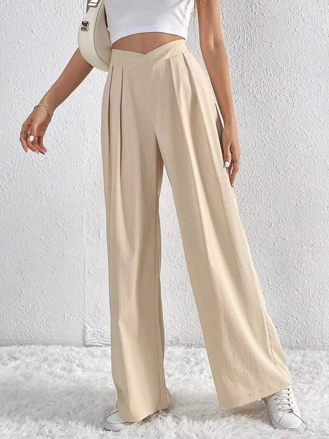 Women's beige wide leg pants with high waist and pleats, front view with sneakers