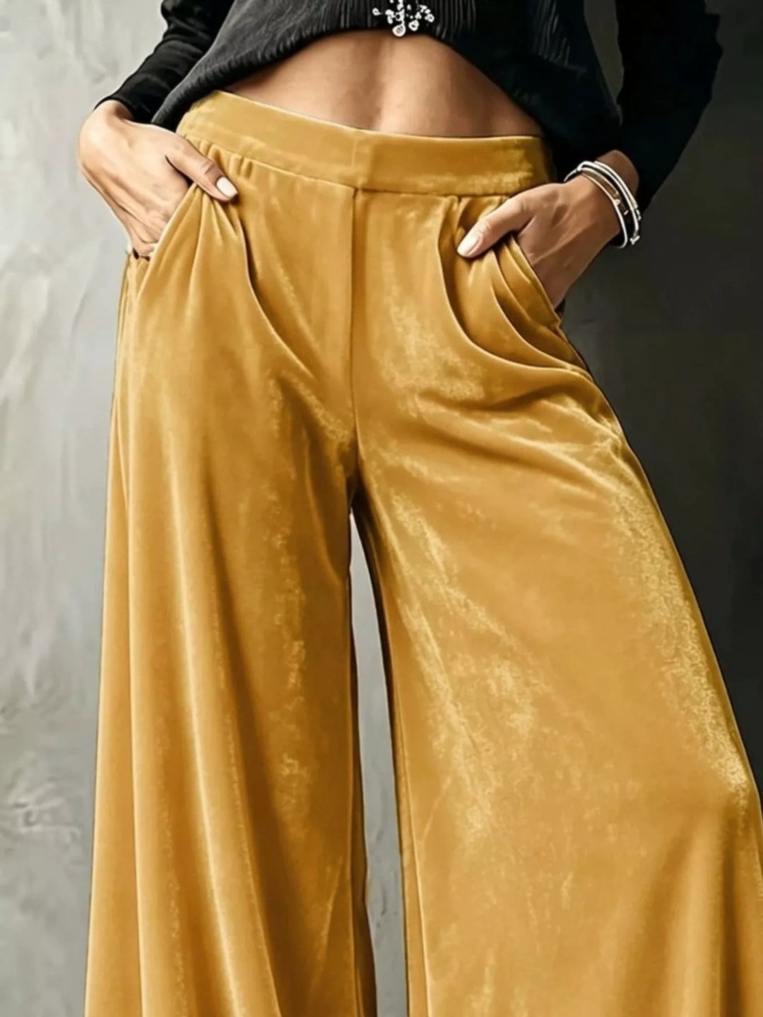 Close-up of mustard wide leg pants with hands in pockets and glossy folds