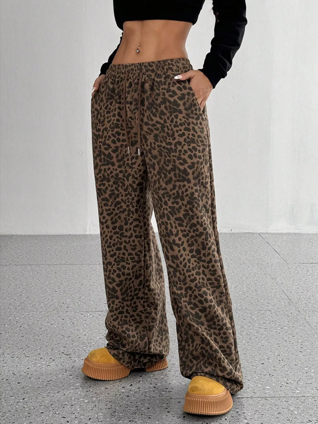 Chocolate leopard print wide leg pants with hands in pockets, front view