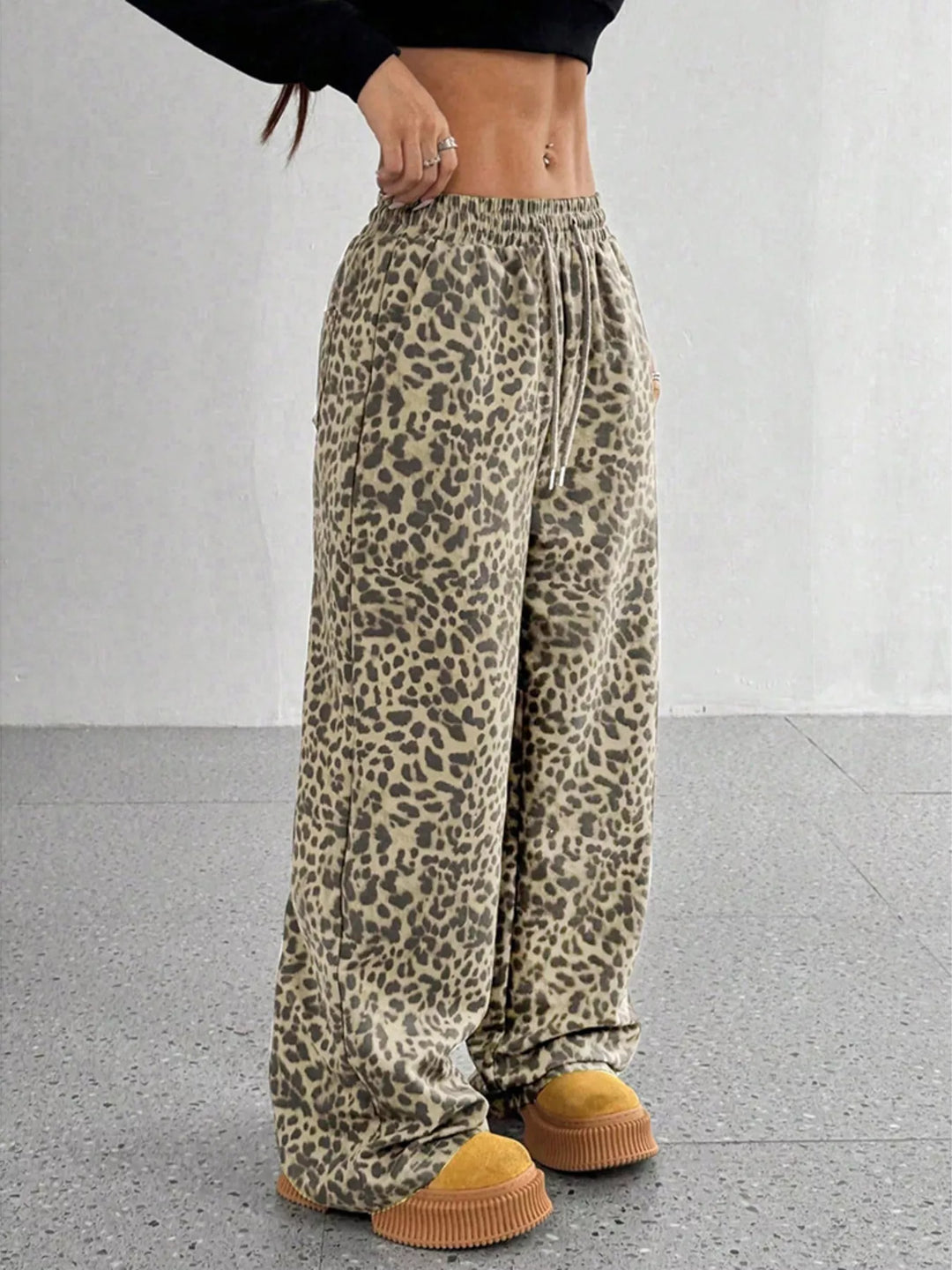 Khaki leopard wide leg pants, angled view with a hand at the waist