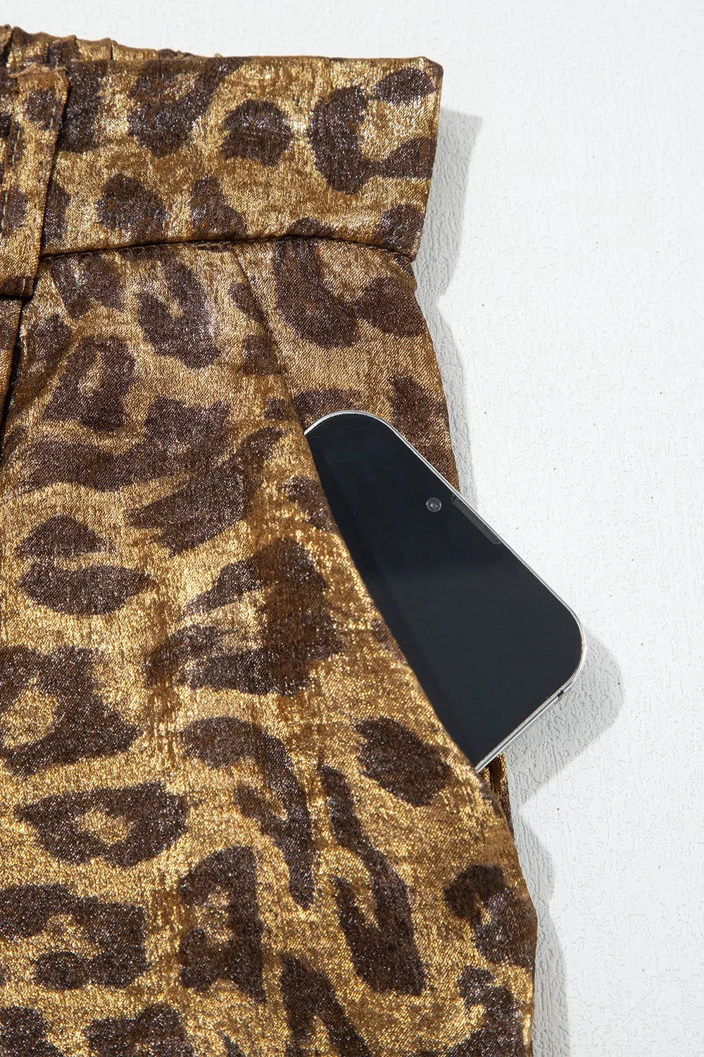 Close-up of the leopard print pants side pocket holding a phone