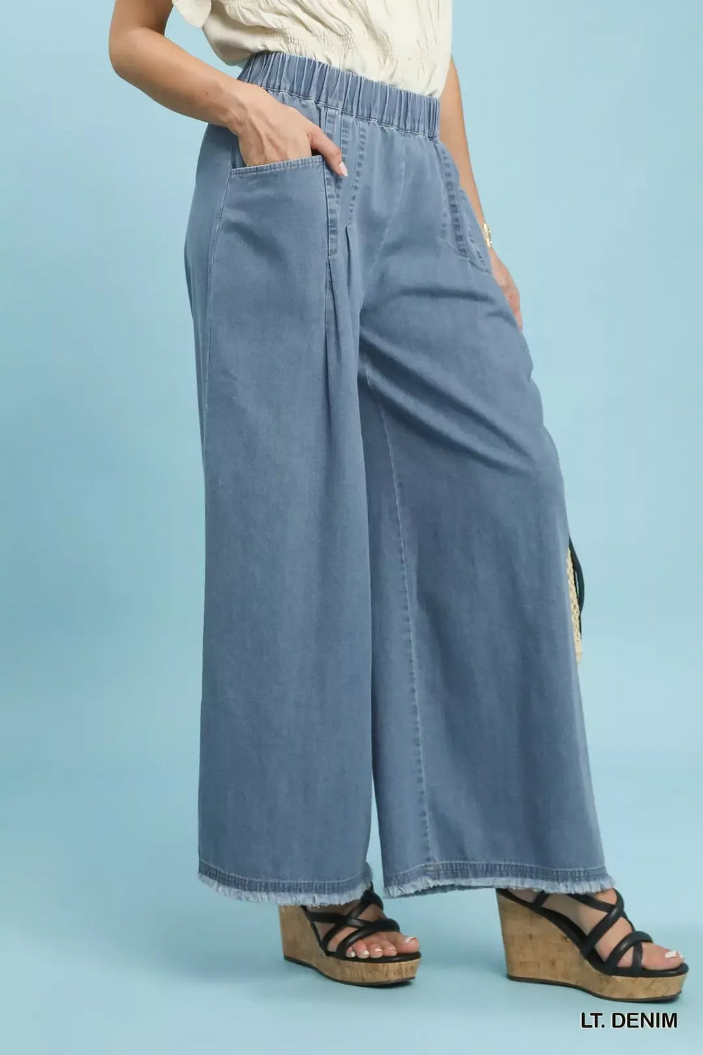 Side view of the light denim wide leg pants with raw hem and pocket