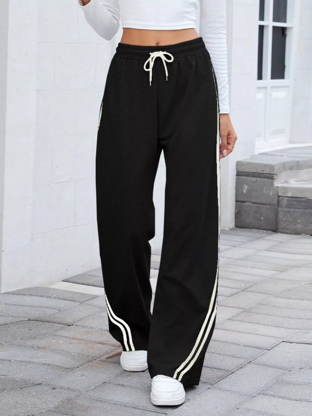Women's wide leg pants in black, side striped drawstring high rise, front view walking