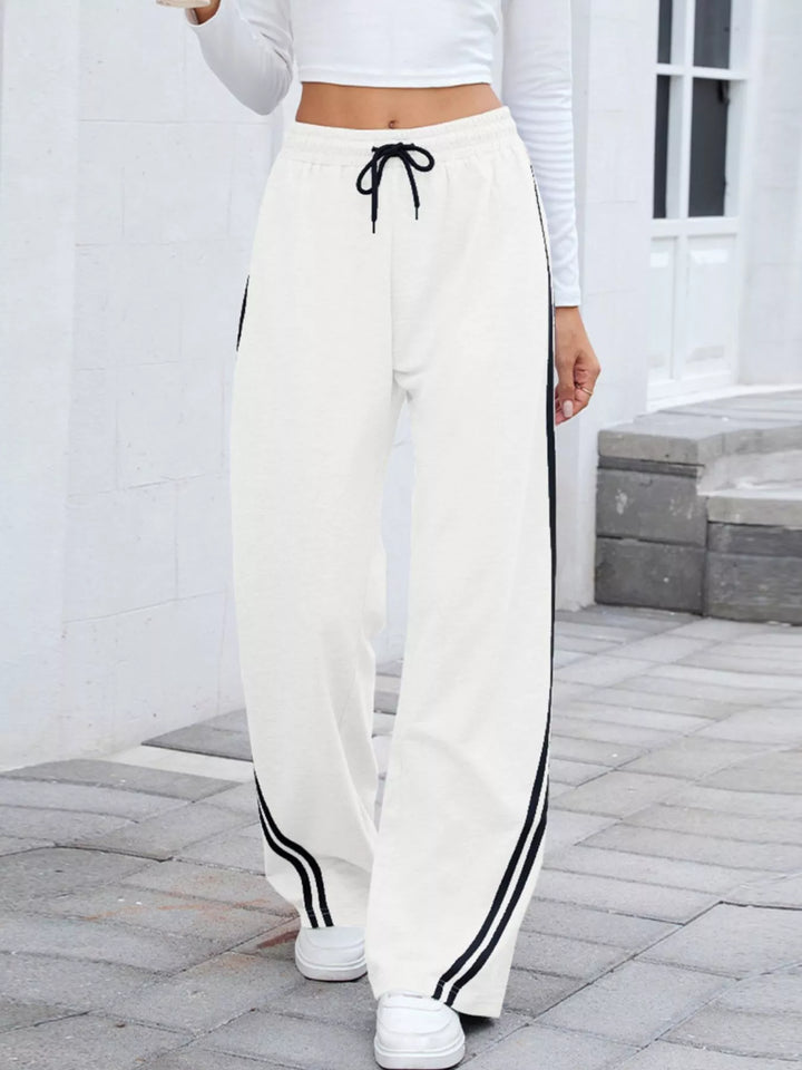 White wide leg pants with black side stripes and drawstring waist, front view