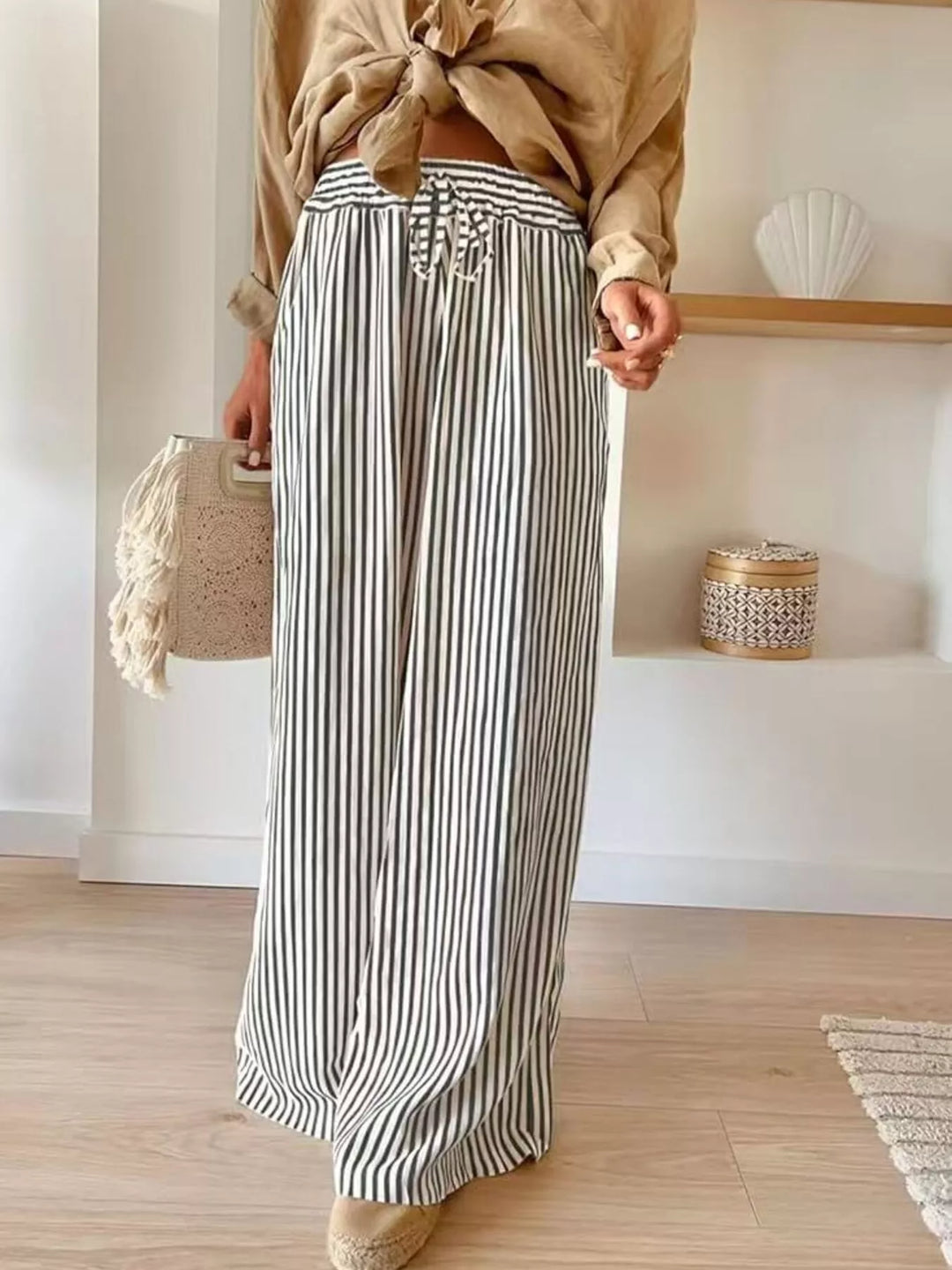 Gray thin stripe wide leg pants with tied tan shirt and woven bag