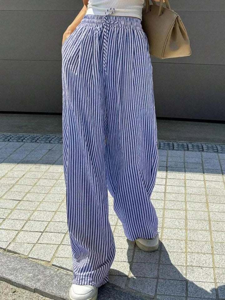 Blue pinstripe pants worn outdoors with a tan bag