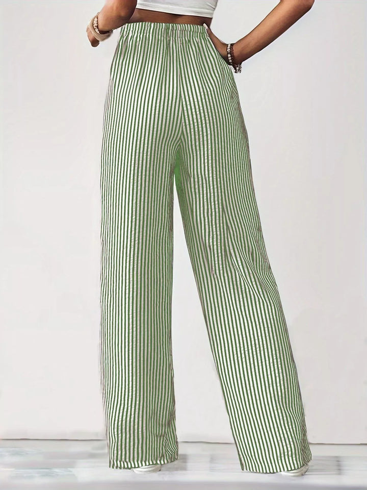 Full length sage pinstripe pants with sneakers against a white backdrop