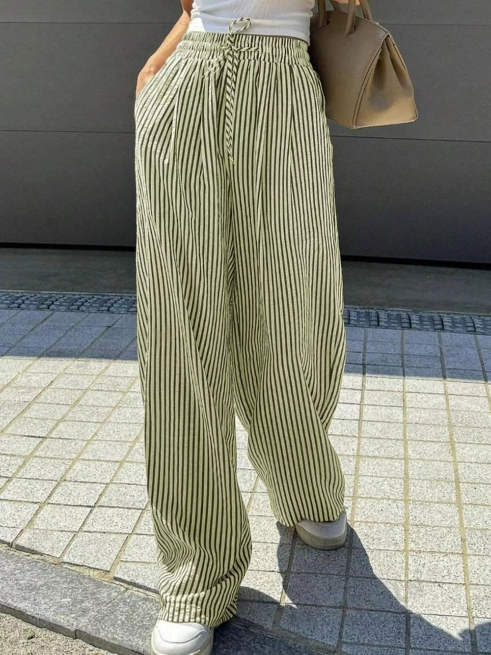 Sage pinstripe wide leg pants worn with a tan bag, walking pose