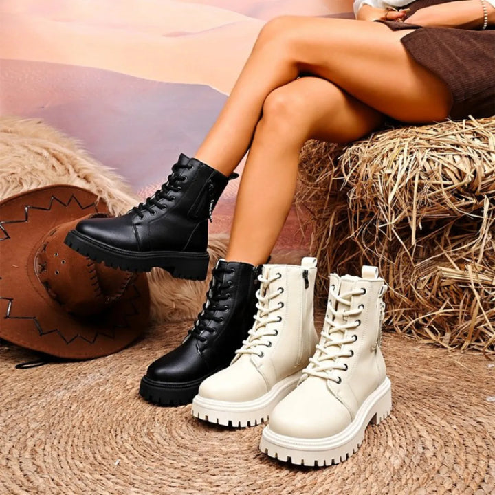 Women's winter boots, lace up platform ankle style, black and ivory pairs on a hay bale