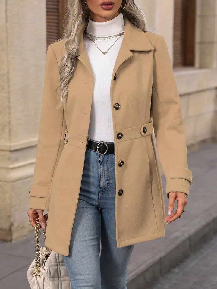 Camel fitted coat open at the front, styled with a belt, jeans and a cream bag
