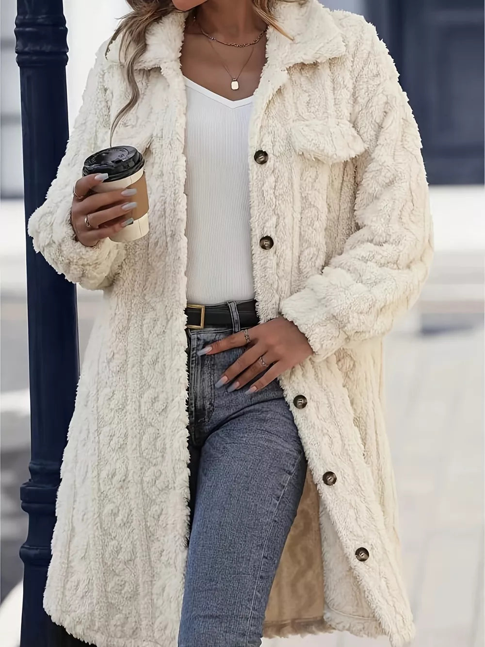 Cream button up winter coat styled with a white tank, jeans and a coffee cup