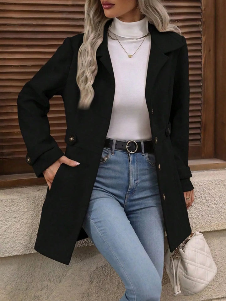 Black single breasted coat worn open with a white top and jeans