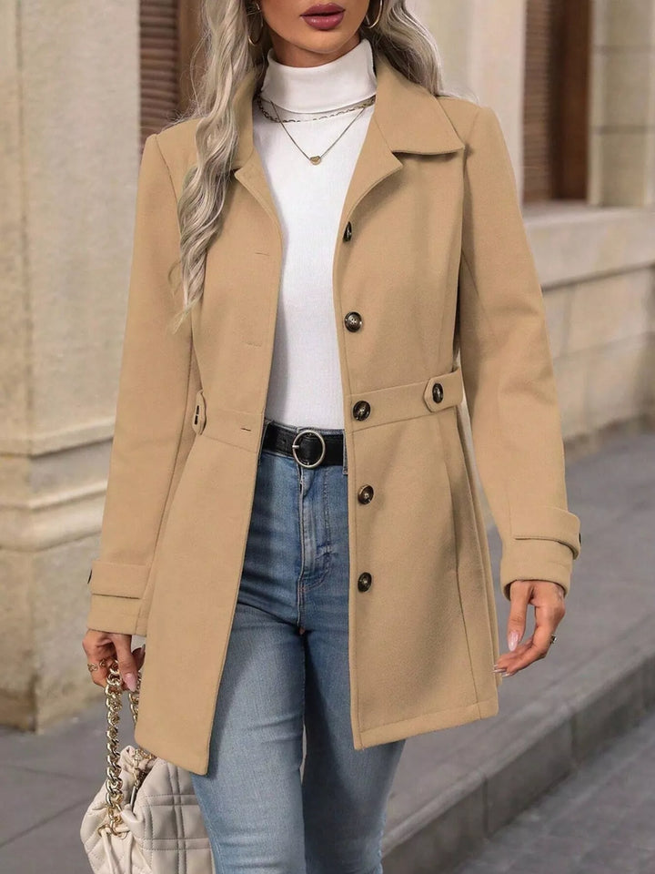 Camel single breasted coat worn open with a white top and jeans