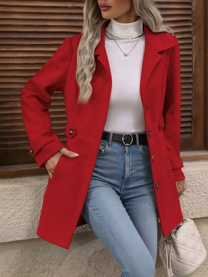 Red collared coat worn open over a white top and jeans